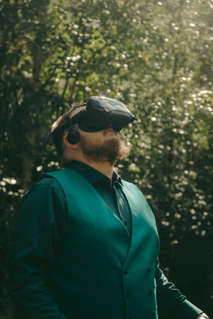Koudilainen katsoo ylös VR-lasit päässään aurinkoisessa metsässä.